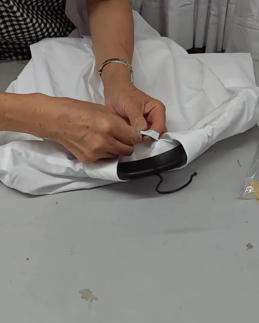 Hands attaching a hangtag to a white garment